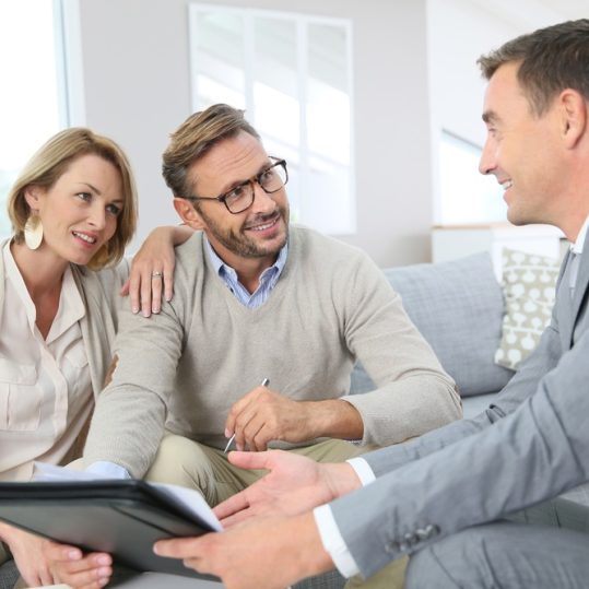 Couple with realtor signing mortgage contract